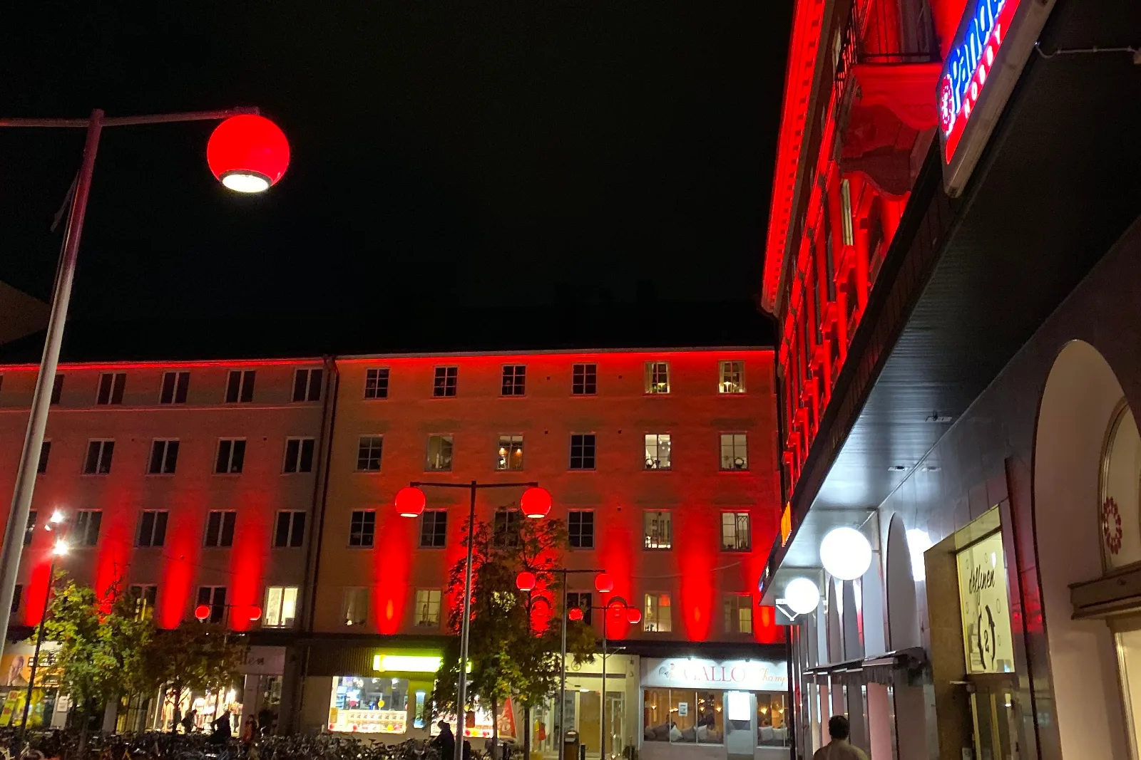 Torg med fasader i rött ljus och röda klotlyktor över gatan